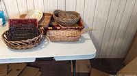 Photo showing variety of 13 wicker baskets in different shapes and sizes on a table