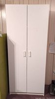 Closed view of the white pantry cabinet showing two doors with handles.