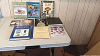Full view of 10 glass collector books spread on table showing covers and titles.