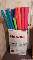 Full view of pool noodles inside original Tundra branded box showing various colors of pool noodles standing upright.