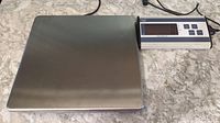 Top view of stainless steel weighing platform connected to digital display unit on a granite countertop.