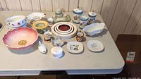 Overview image showing all vintage kitchen and decorative ceramic and porcelain pieces arranged on a white folding table.