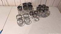 Top view showing multiple glassware sets with metallic luster finish arranged on table including racks with highball and sherry glasses plus additional small glasses.