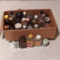 Box of assorted vintage and antique glass bottles with varied caps and labels