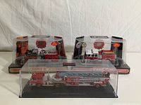 Three Code 3 collectible fire truck models, two in original packaging and one in a clear display case.