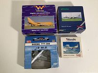 Four boxed collectible airplane models shown from above: Braniff International Boeing 747SP, Alitalia Boeing 747-200, All Nippon Airways Boeing 777-300, Nordic European Airlines Lockheed L-1011-50