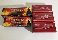 Five sealed boxed Corgi Heroes Under Fire 1:50 scale fire truck models, with two larger packs and three smaller red boxes showing different fire truck models.