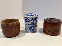 Porcelain container and wooden case displayed disassembled, showing the hand-painted blue and white porcelain cylinder with lid and two wood case pieces.
