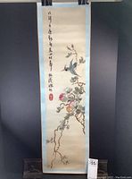 Full view of the Japanese scroll showing embroidered birds on flowering branches and calligraphy.