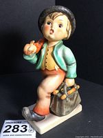 Front view of M.I. Hummel Merry Wanderer figurine showing boy walking with a bag of sticks and umbrella.