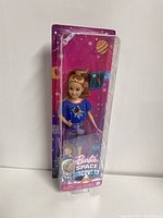 Front view of Barbie Space Discovery Stacie doll in packaging showing doll in blue astronaut shirt, space pants, and pink accessories.