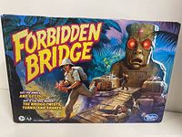 Front and side views of Forbidden Bridge board game box showing colorful game artwork and branding.
