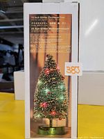 Photo of the packaging box showing the 10 inch glitter Christmas tree with LED lights and battery-powered base.
