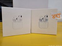 Two white boxed sets of wireless Bluetooth earbuds shown front facing.
