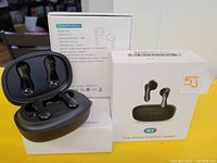 Three black M2 wireless Bluetooth earbuds each in their open charging case, showing the earbuds inside and specification info on box in background.