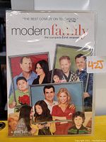 Photo of Modern Family complete first season DVD 4-disc set in shrink wrap showing cover art with cast photos.