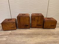 Four Baribo Maid solid wood kitchen canisters on floor, showing different sizes and labels for Tea, Sugar, Flour, and Coffee.