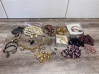 Full assortment of vintage and retro costume jewelry including necklaces, bracelets, and clip-on earrings displayed on floor