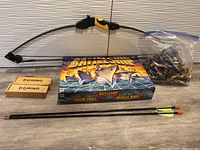 Lot contents including toy bow, arrows, domino sets, Battleship game box, and bag of action figures.