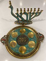 Photo of brass Passover Seder plate and brass menorah shown on countertop, highlighting design and size