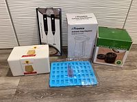 Full lot photo showing all five sealed items in original packaging arranged on tiled floor against textured wall.