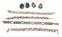 Overview of the four silver bracelets and two pairs of earrings with turquoise and malachite stones displayed on a white surface.