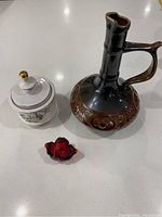 Top-down view of three items: ceramic wine jug, red glass basket, and white ceramic sugar dish with bird motif