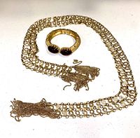Photo of a vintage gold-tone pearl draping necklace and a gold-tone bracelet with red stones on a white surface