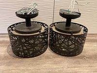 Two bronze metal chandeliers shown upside down revealing wiring and mounting plate, showcasing overall design and condition.
