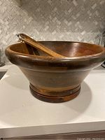 Side view of large wooden salad bowl with tossers resting inside