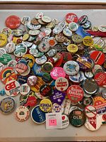Overview of assorted pins and buttons with varied slogans and graphics spread on a flat surface.