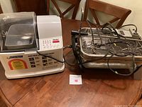 Photo showing the Welbilt convection bread machine on left and Farberware countertop rotisserie with cords and metal parts on right.
