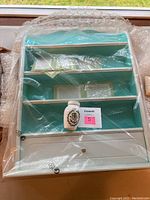 White Franklin Mint spice rack in bubble wrap with one unwrapped ceramic jar on shelf.