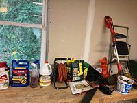 Shelving with assorted gardening chemicals, sprayers, hose reel and electric garden tools