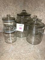 Full set of six clear glass canisters with lids, various sizes, displayed together on a countertop.