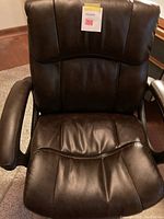 Front view of chocolate faux leather office chair highlighting padded seat, backrest, and armrests with height adjustment sticker.