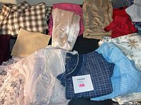 Overview of women's clothing including plaid shirts, blouses, knit tops, patterned pants and shorts mostly size small.