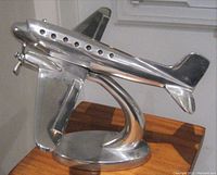 Side angle showing the airplane statue detailing and stand on wooden surface.
