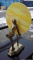 Front view of lamp showing nude figure and circular sunset swirl glass shade
