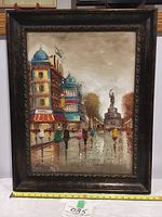 Framed colorful impressionist oil painting showing a Paris street with buildings and people, signature visible at the bottom