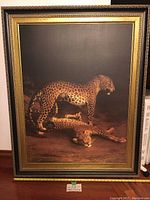 Framed reproduction on canvas of two leopards, standing and lying on a dark background, showing full front view including frame details and bottom measuring tape.