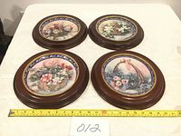 Set of four mounted porcelain plates with flower bucket bouquet prints, 11-inch wooden mounts visible, tape measure showing size.