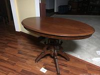 Overall side view of vintage oval hardwood table showing the shape, wood finish, and condition.