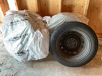 Four tires, three wrapped in Michelin-branded plastic bags and one exposed tire on steel rim.