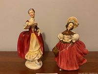 Front view of two Royal Doulton ladies figurines in red dresses with detailed features and colors.