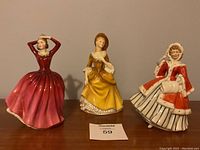 Three figurines side by side on wooden surface