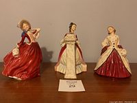 All three Royal Doulton figurines arranged on a wooden surface, front view