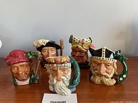 Front view of 5 Royal Doulton Toby mugs showing detailed character faces and colorful headgear.