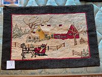 Full view of the antique hooked rug showing winter scene with horse-drawn carriage and houses.