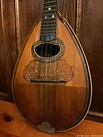 Front view of mandolin showing decorative inlay, teardrop-shaped soundhole, and split along body